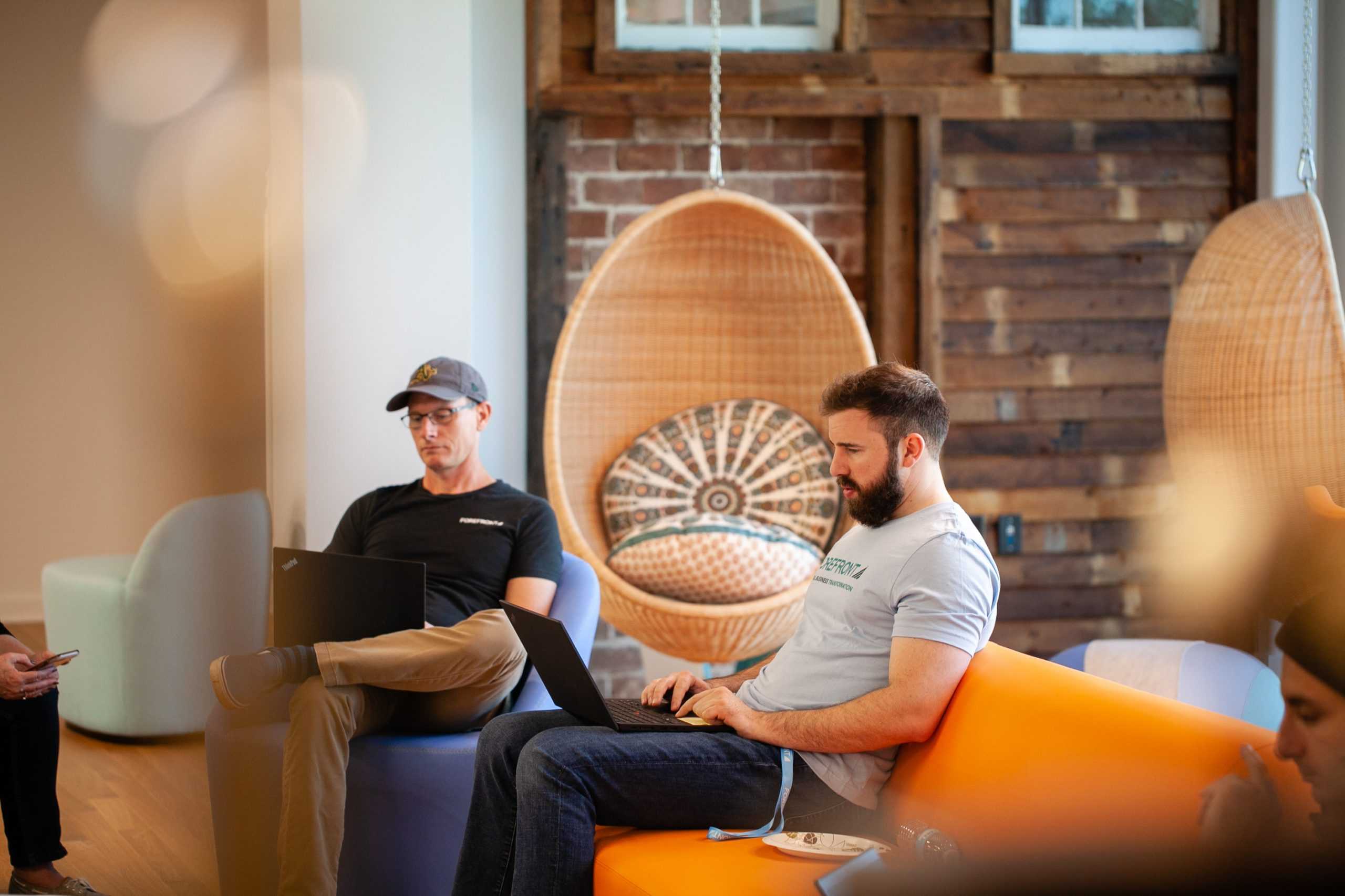 Two people working on laptops in a brightly lit, modern office.
