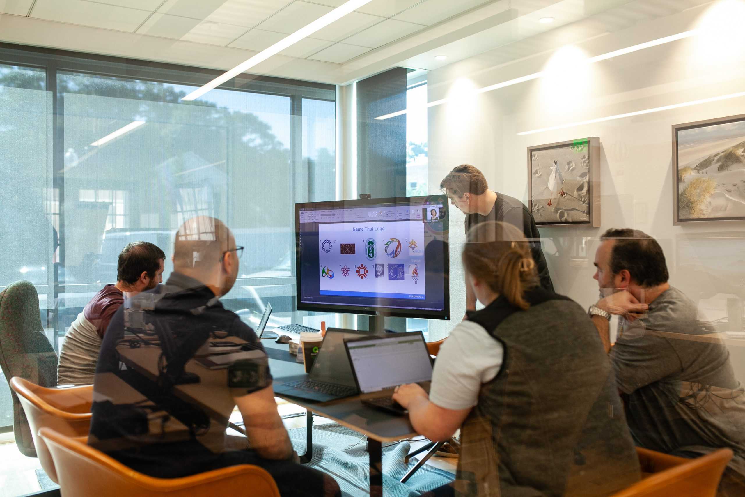 Group of people at table with laptops and projector in meeting room,