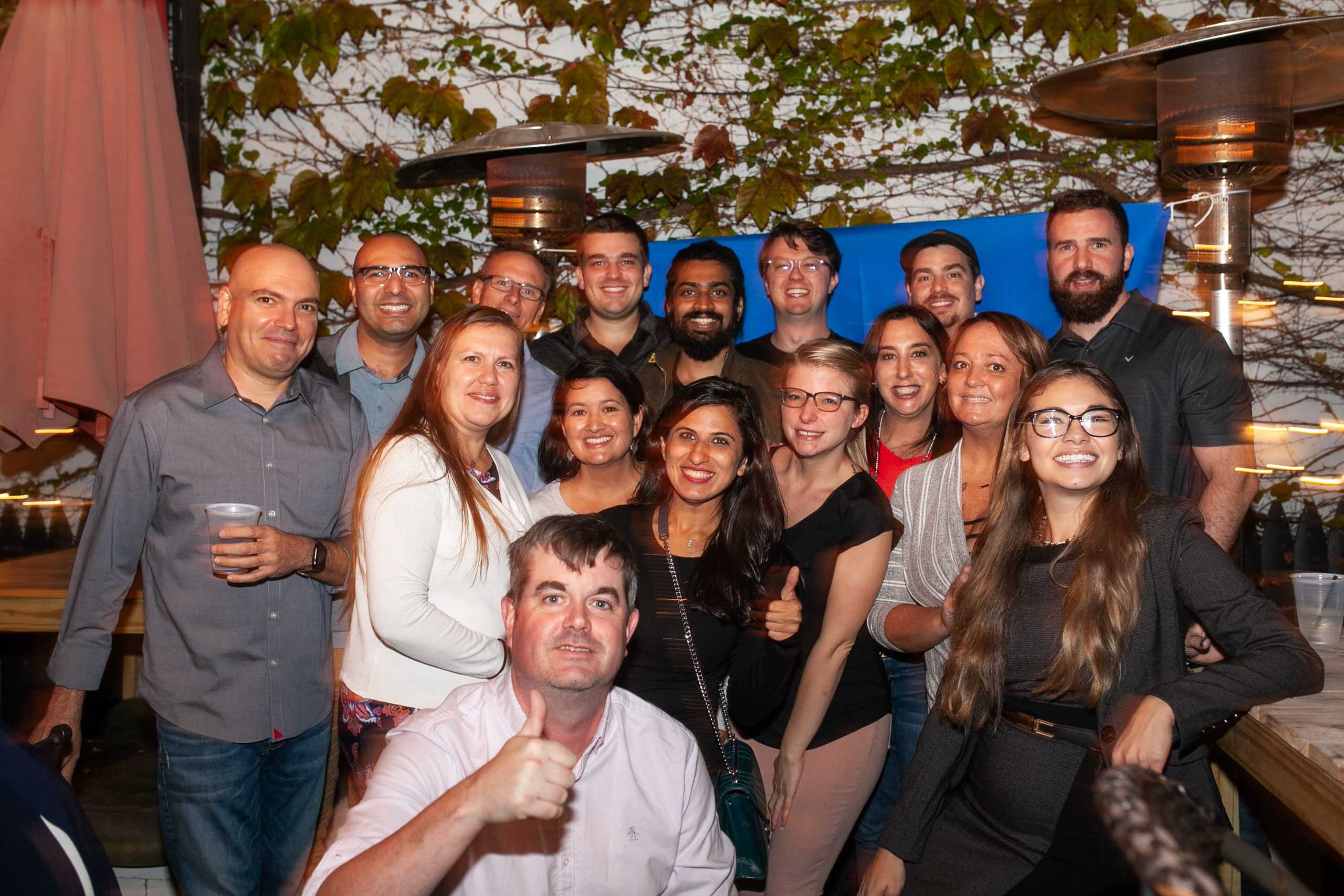 A group photo of 16 smiling people at a work event.