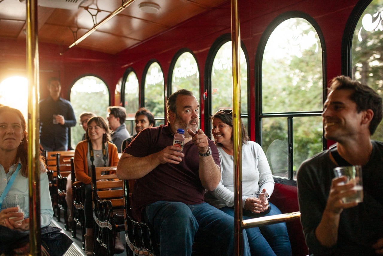 4FDay_2021_1-scaled Large A man and woman sitting in a trolley car, smiling at the camera. They are surrounded by other people, also enjoying the experience.
