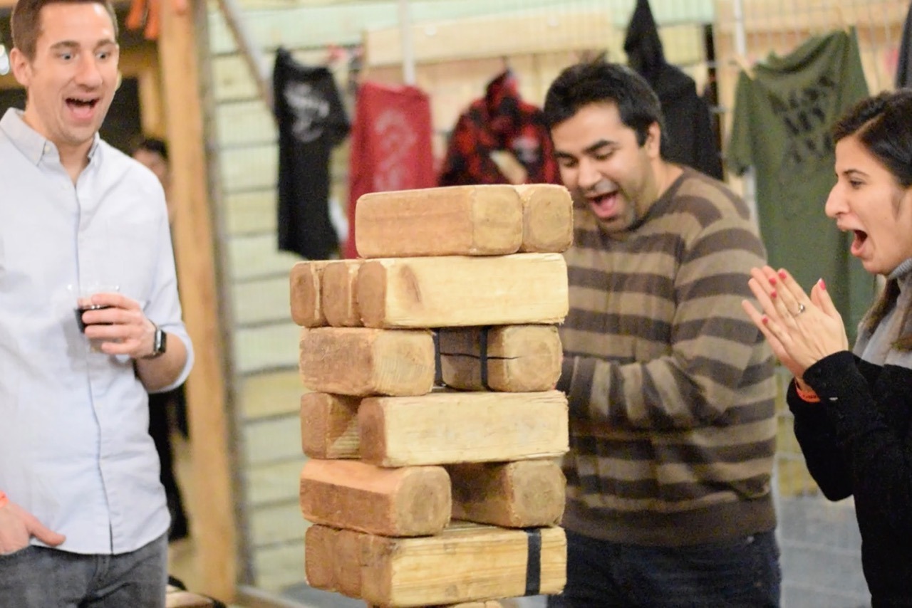 C-Slideshow15 Large Three people excitedly playing giant Jenga.